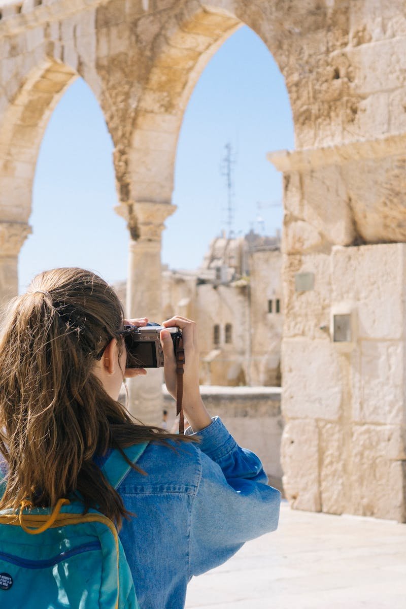 A tourist photographs the ancient stone arches in Jerusalem's Old Town, capturing the essence of travel and history.
