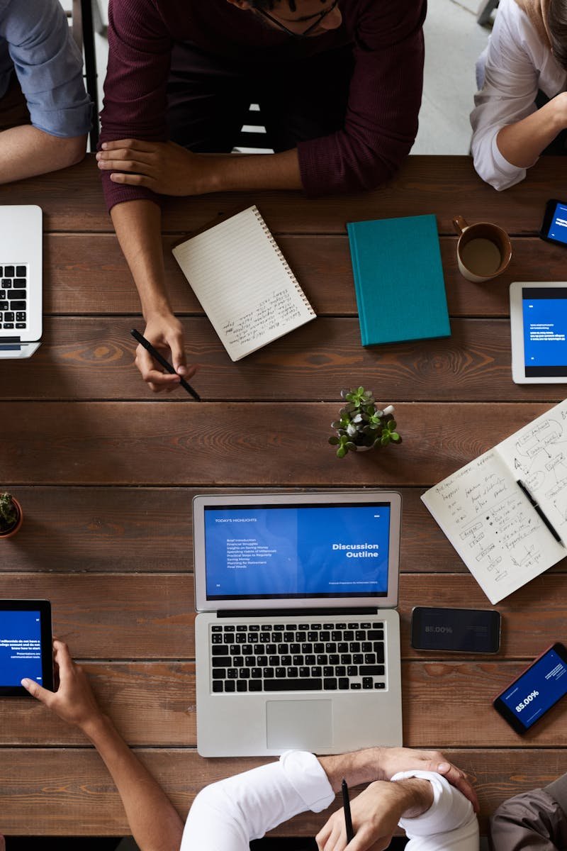Overhead view of a diverse team in a business meeting using laptops and tablets.
